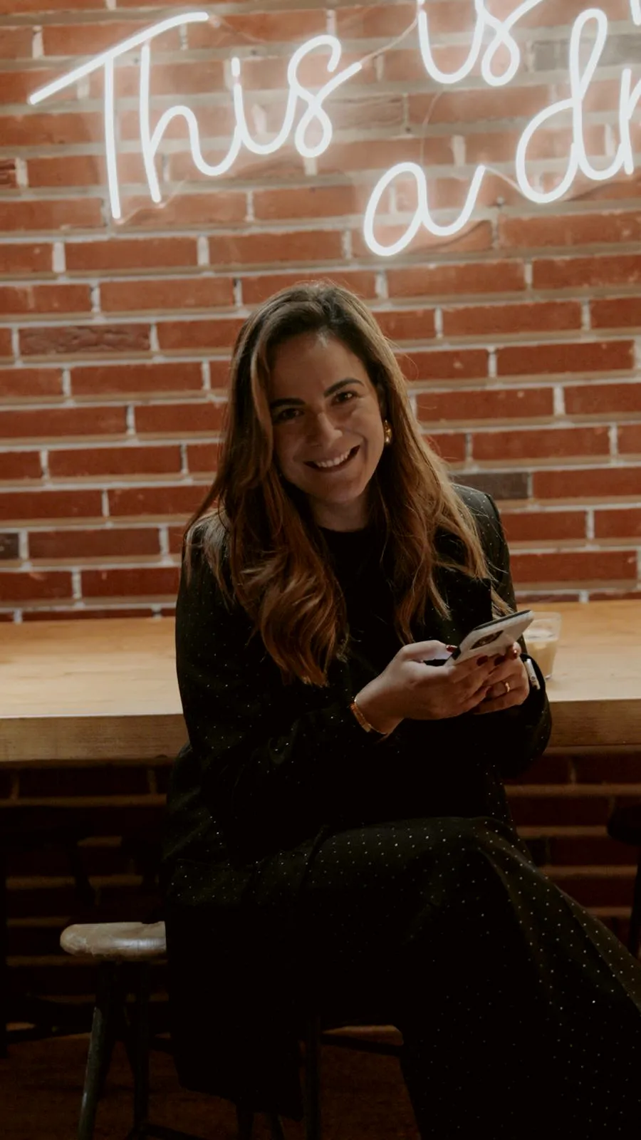 Filipa sentada junto a uma parede de tijolo, a sorrir, antes de um encontro anterior ao clube.